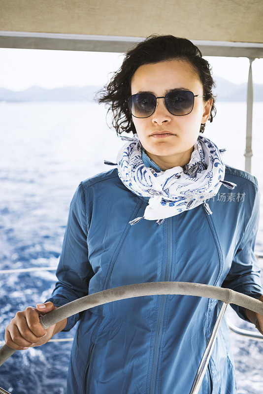 Woman using the boat's wheel, sailing